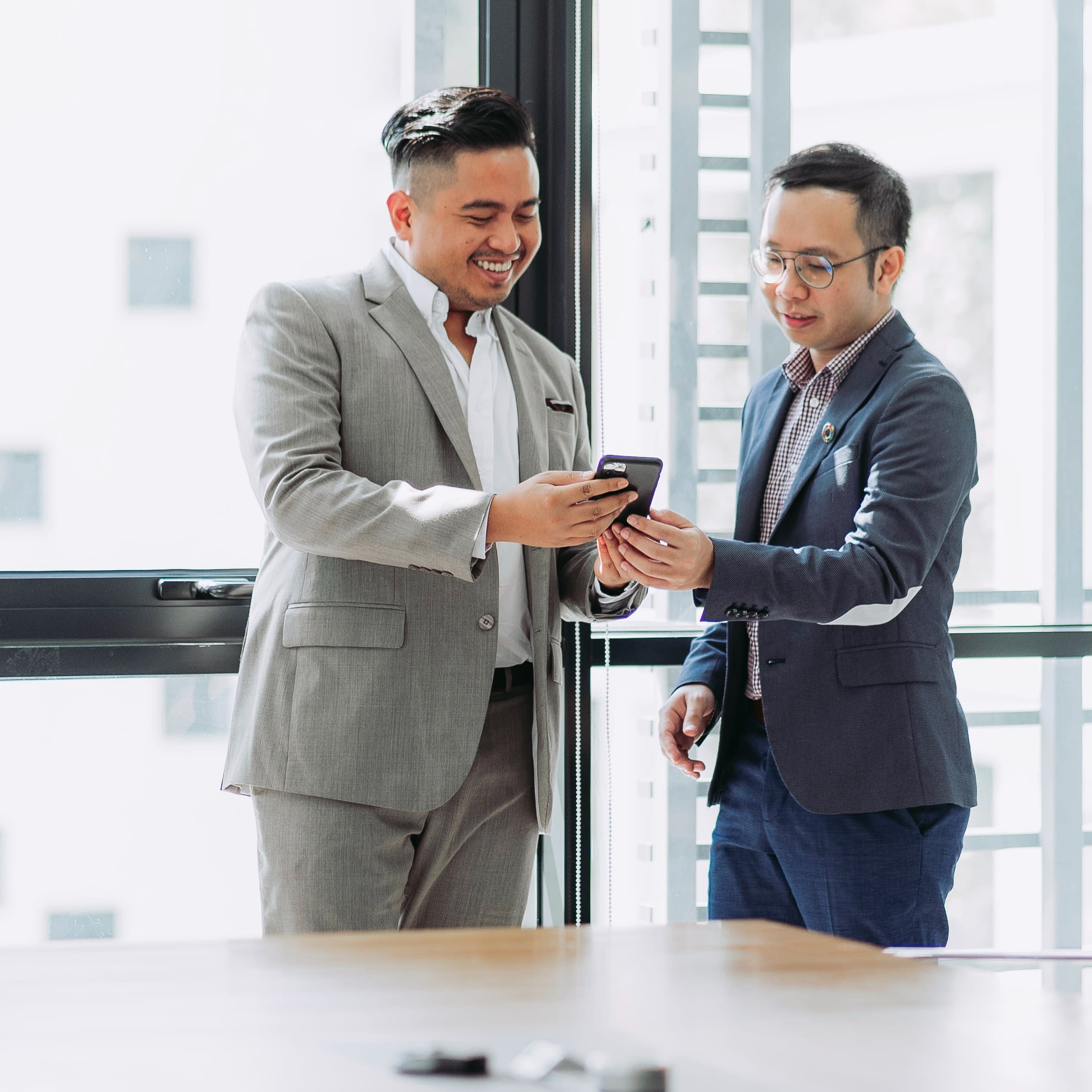 Two men looking at something on a cellphone.